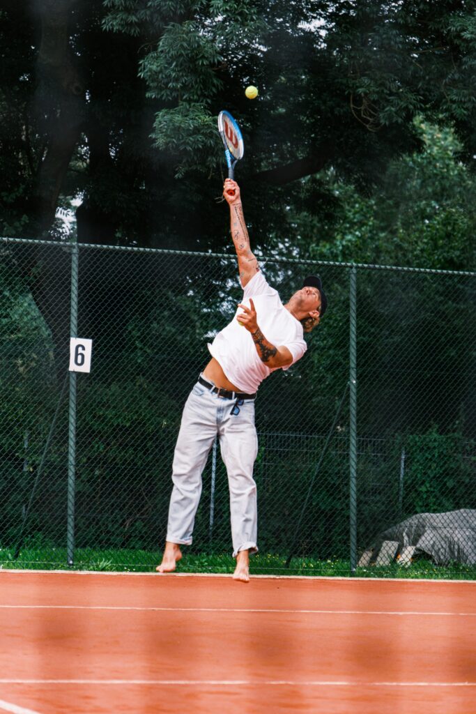 Joueur de tennis au service sur un court en terre battue